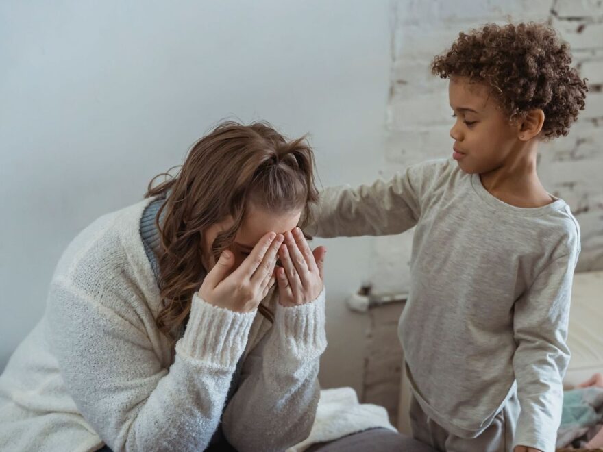 Vuxen tröstar ett upprört barn medan ett annat barn står bredvid